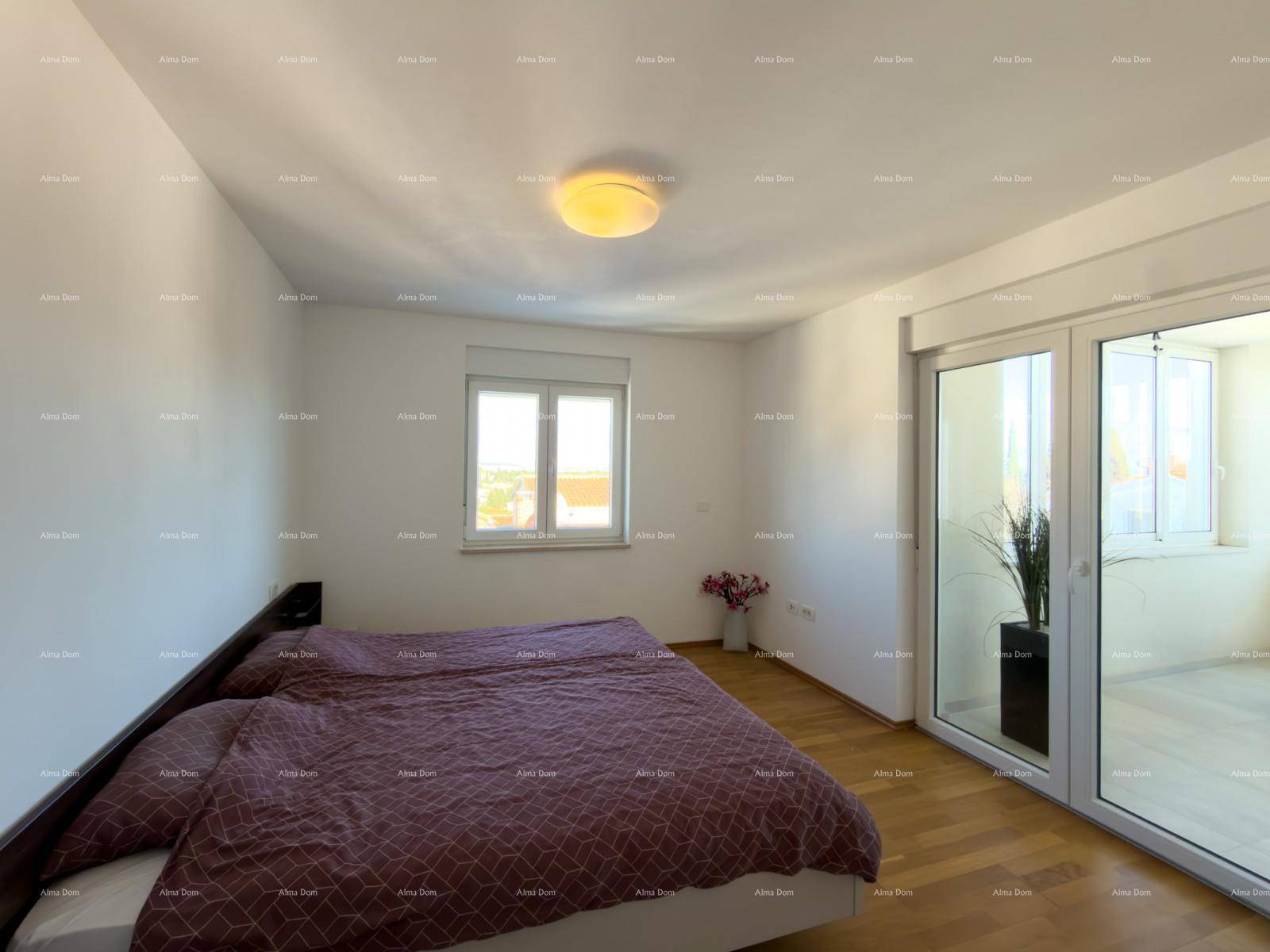 Helles Schlafzimmer mit Holzboden, Doppelbett und Zugang zu einem verglasten Balkon.