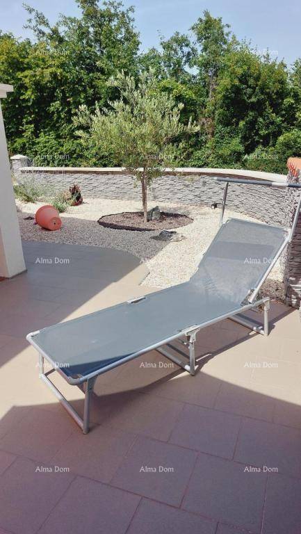 Sonniger Terrassenbereich mit Liegestuhl und Blick auf die mediterrane Bepflanzung.