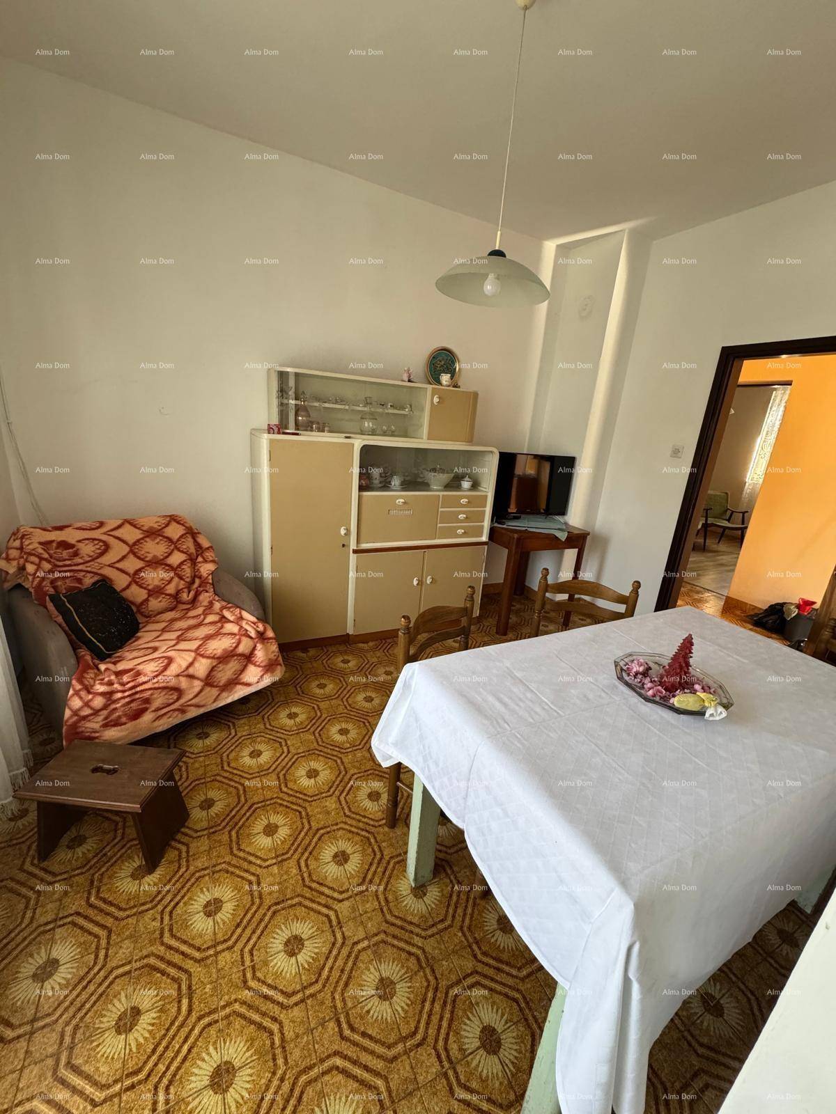 Esszimmer mit Esstisch, Stühlen und einem Schrank, mit gemustertem Fliesenboden.