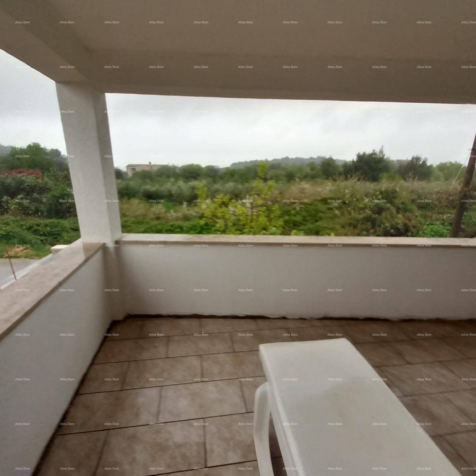 Überdachter Balkon mit Fliesenboden und Liegestuhl, bietet einen weiten Blick ins Grüne.