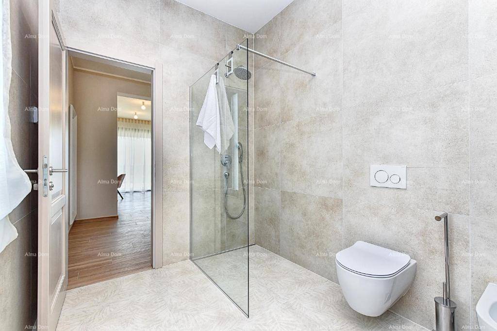 Badezimmer mit begehbarer Dusche, Wand-WC und hellen Fliesen, offen zu einem Flur.