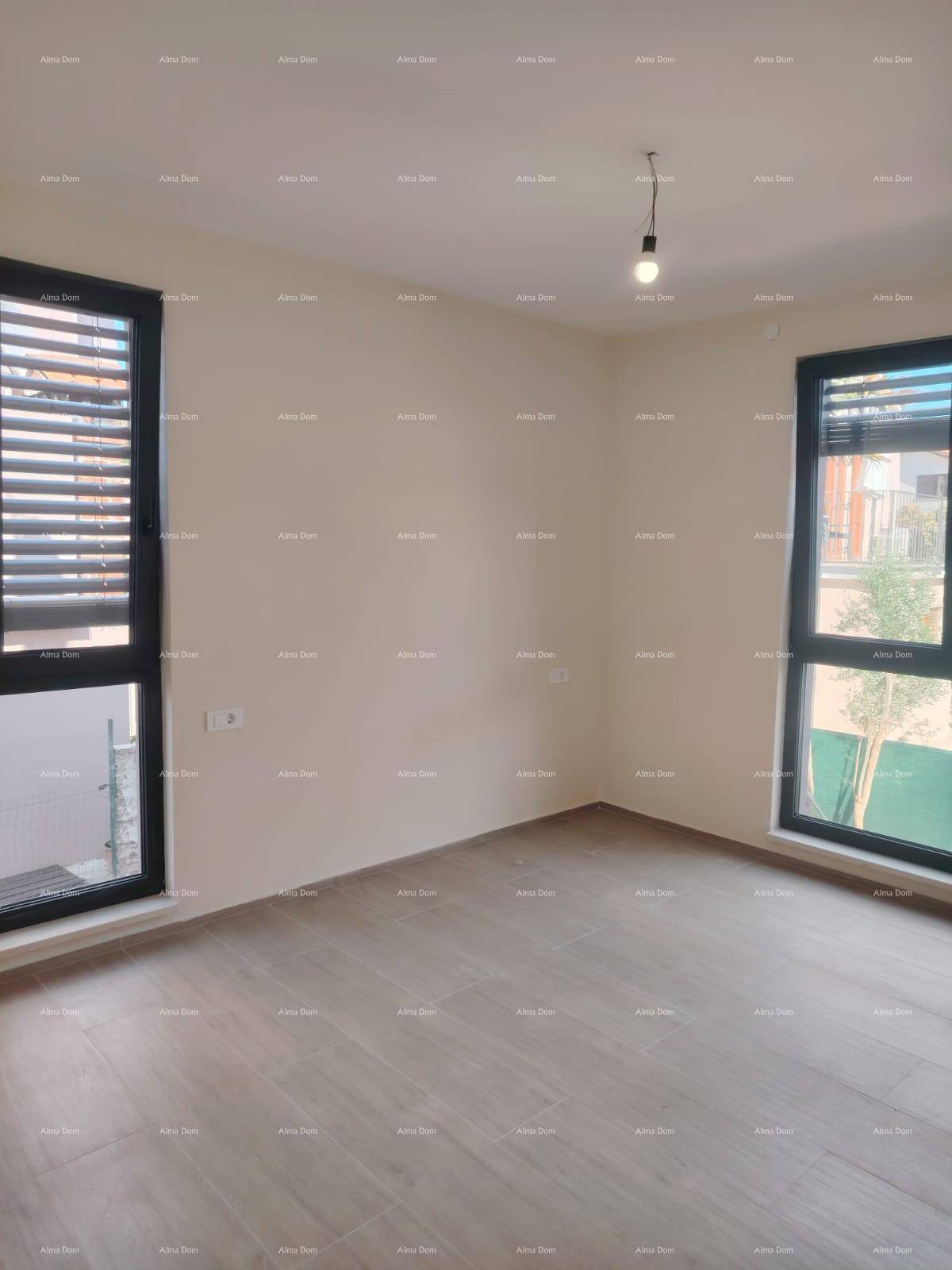 Leeres Schlafzimmer mit hellen Wänden, zwei großen Fenstern und modernem Fliesenboden in Holzoptik.