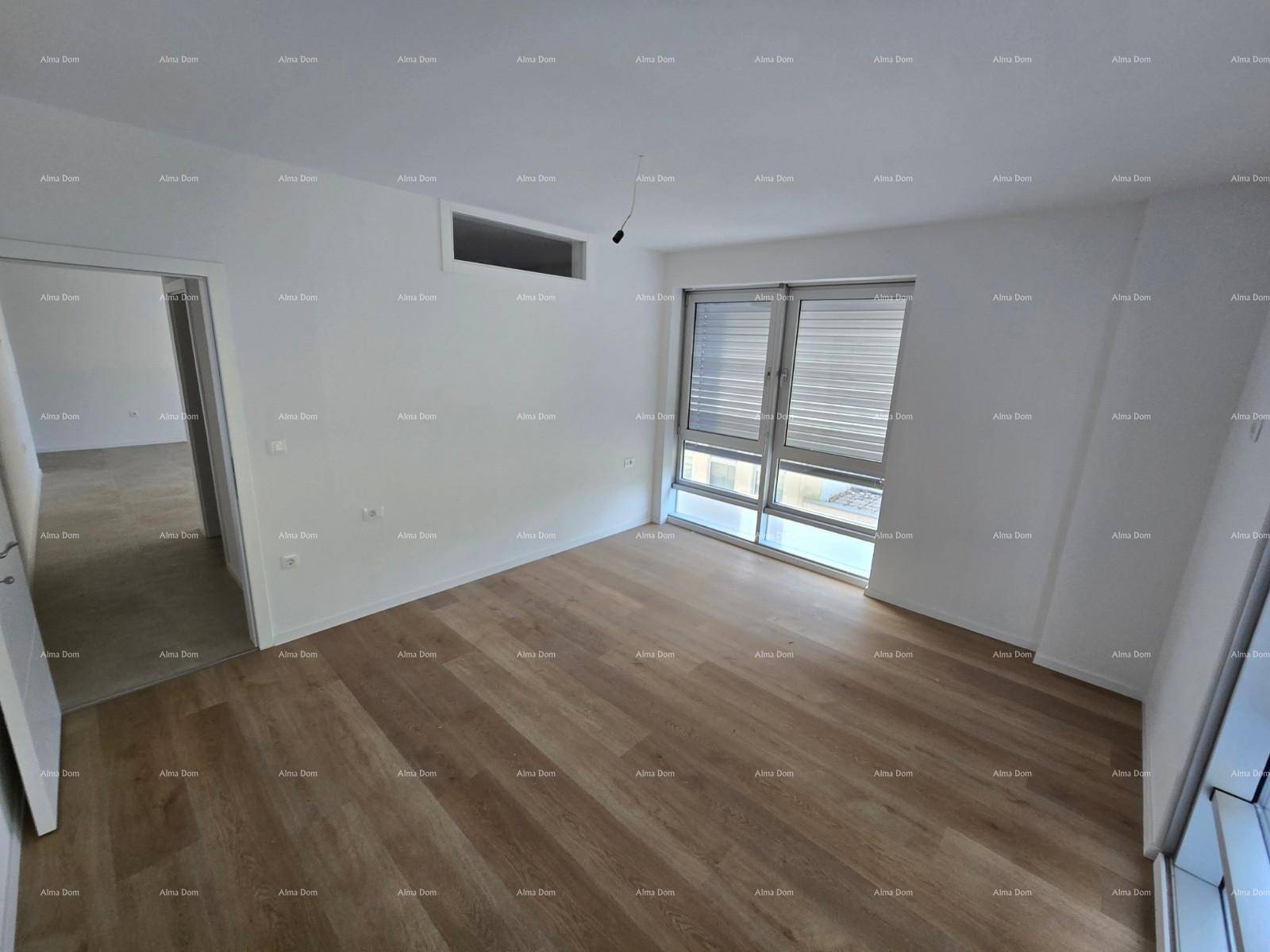 Geräumiger Raum mit Holzfußboden, großen Fenstern und Zugang zu einem weiteren Bereich.