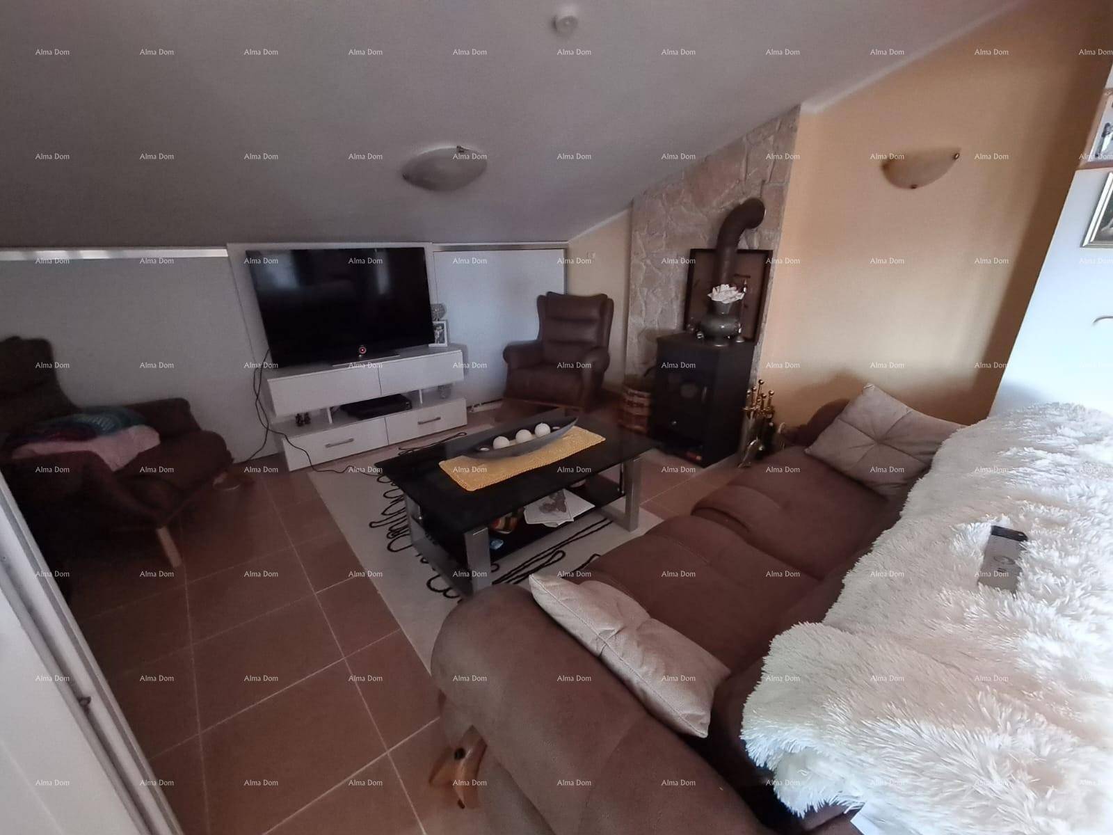 Wohnzimmer im Dachgeschoss mit Sofa, Fernseher und einem Holzofen für gemütliche Abende.