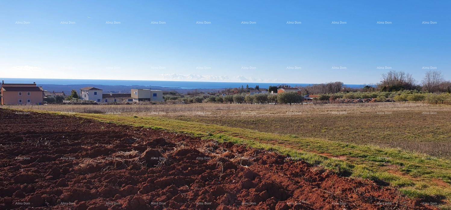 Weitläufige Landschaft mit Feldern, Gebäuden und dem Meer in der Ferne.