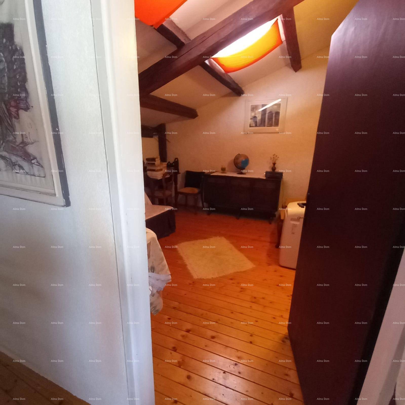 Schlafzimmer mit Holzboden, sichtbaren Deckenbalken und einem Fenster, das Tageslicht spendet.