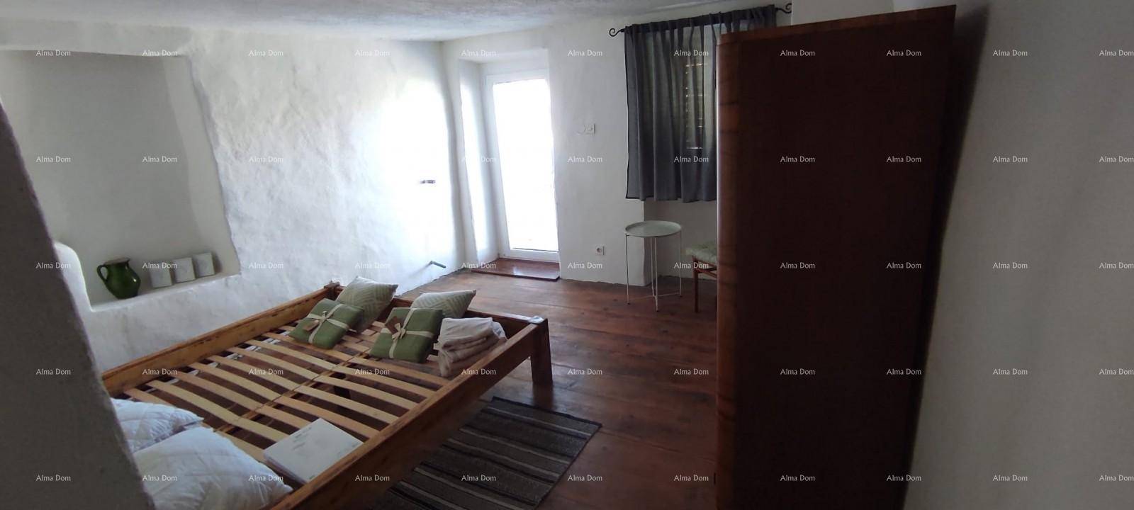 Helles Schlafzimmer mit Holzbett, Holzboden und einem Fenster mit dunklen Vorhängen.