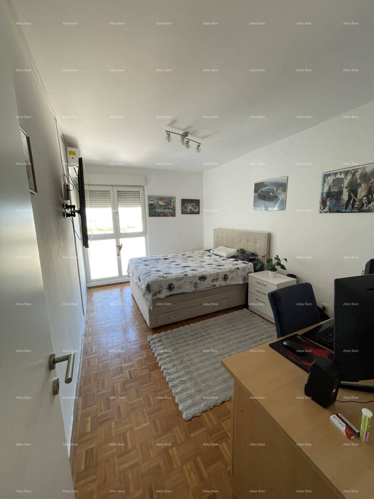 Schlafzimmer mit Parkettboden, Doppelbett und Schreibtischbereich neben dem Fenster.