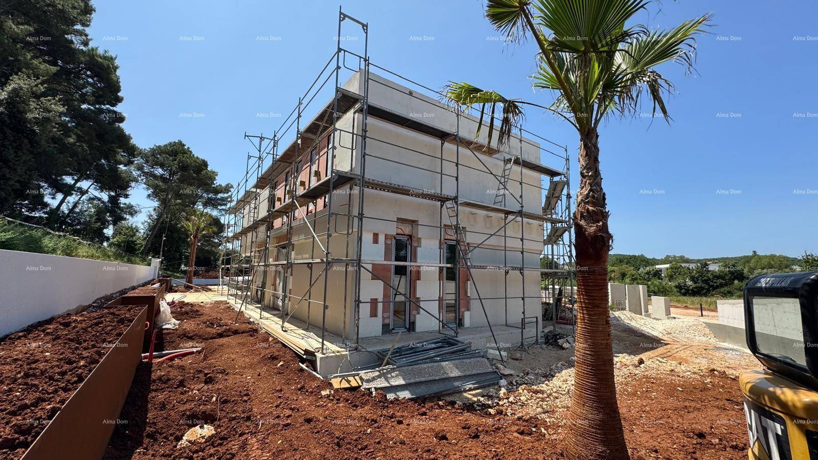 Baustelle eines modernen Hauses mit Gerüst und beginnender Fassadenverkleidung unter blauem Himmel.