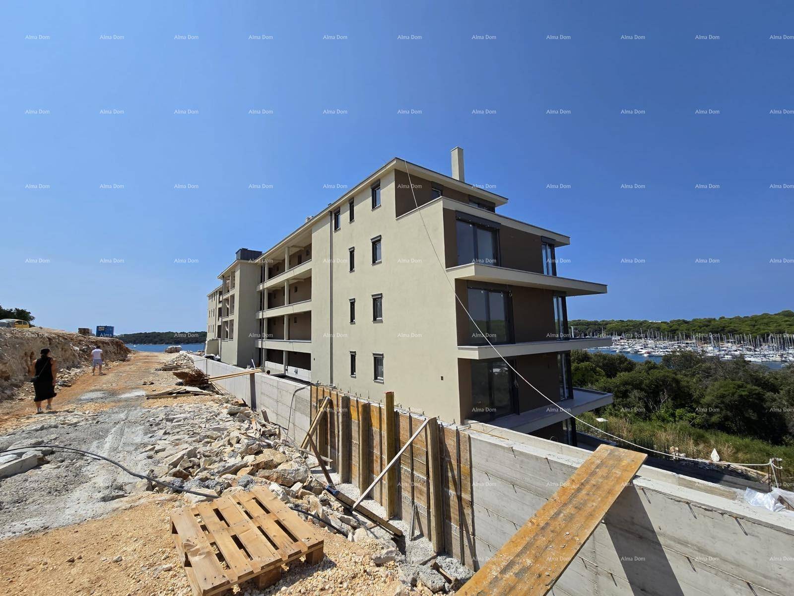 Modernes Gebäude im Bau mit beiger Fassade und Blick auf den Yachthafen am Meer.