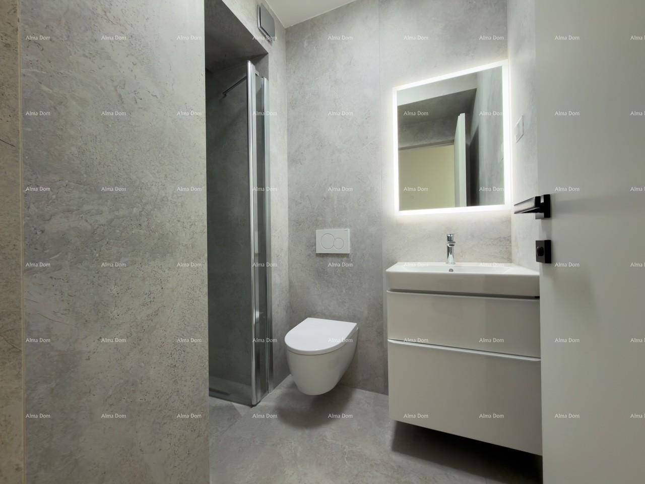 Modernes Badezimmer mit grauen Fliesen, wandhängender Toilette und beleuchtetem Spiegel.