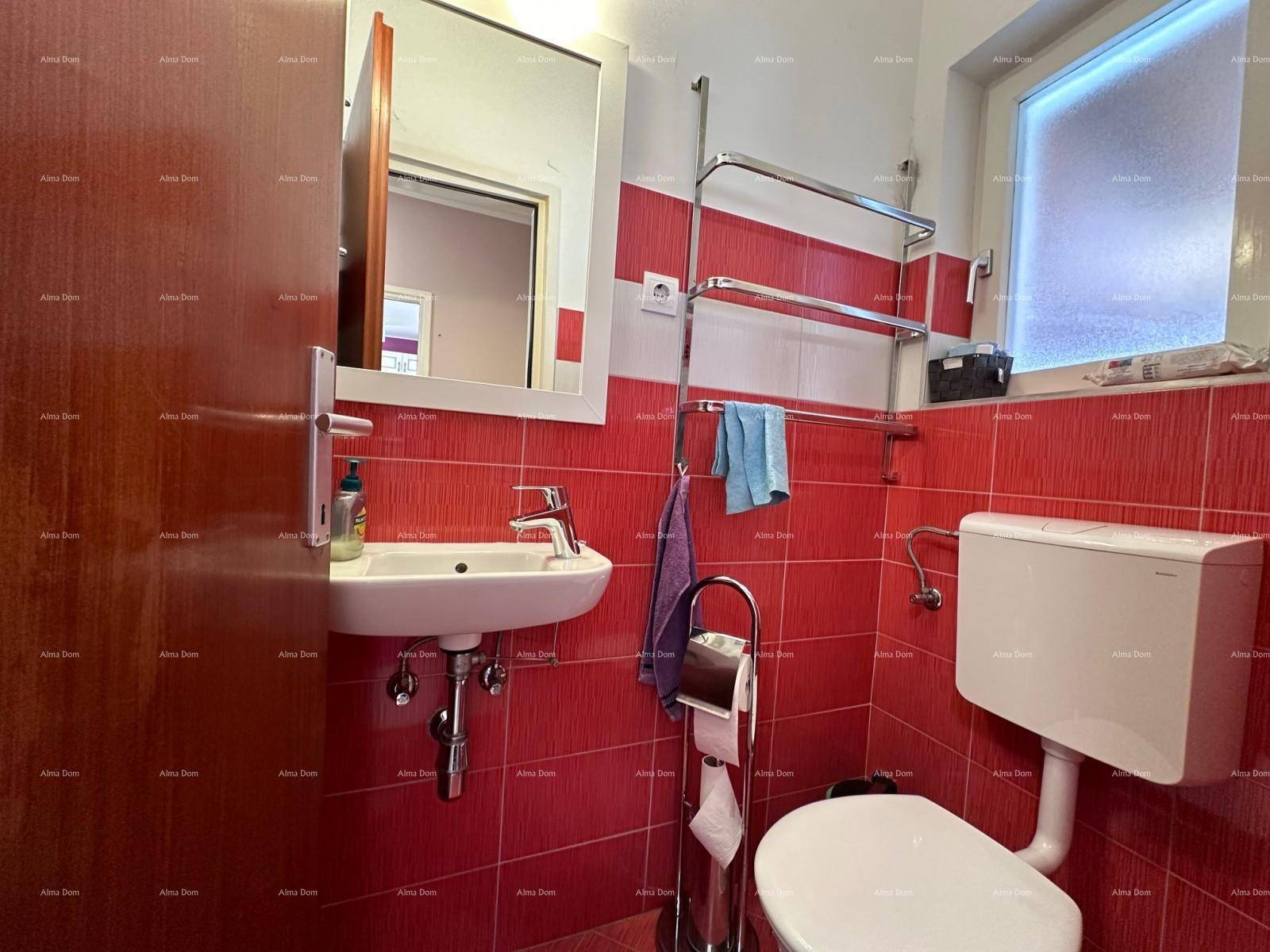 Kleines Badezimmer mit roten Fliesen, Waschbecken, Toilette und Fenster für Tageslicht.