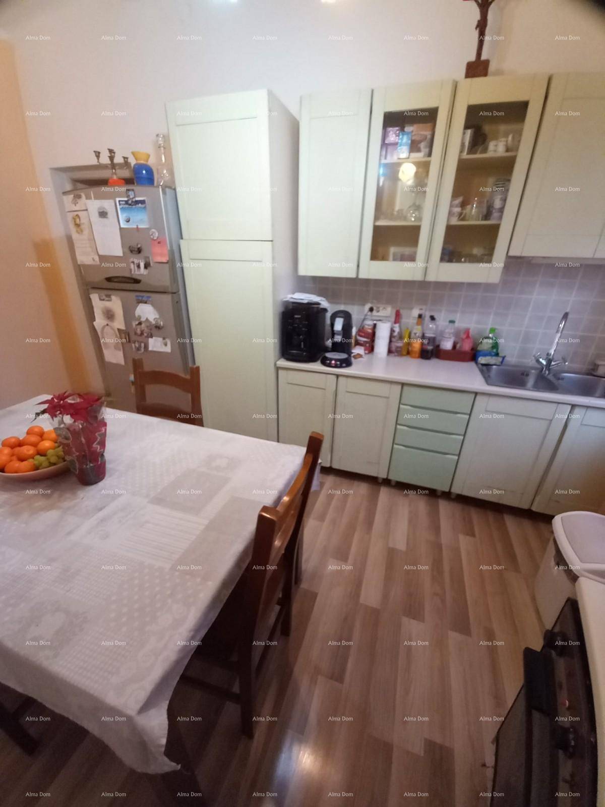 Helle Küche mit Esstisch, Kühlschrank und hellgrünen Schränken, bereit zur Nutzung.