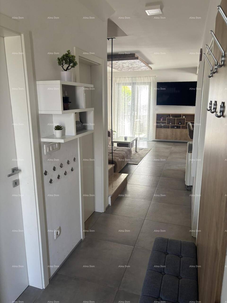 Heller Flur mit Fliesenboden, Garderobe und Blick in den offenen Wohnbereich.