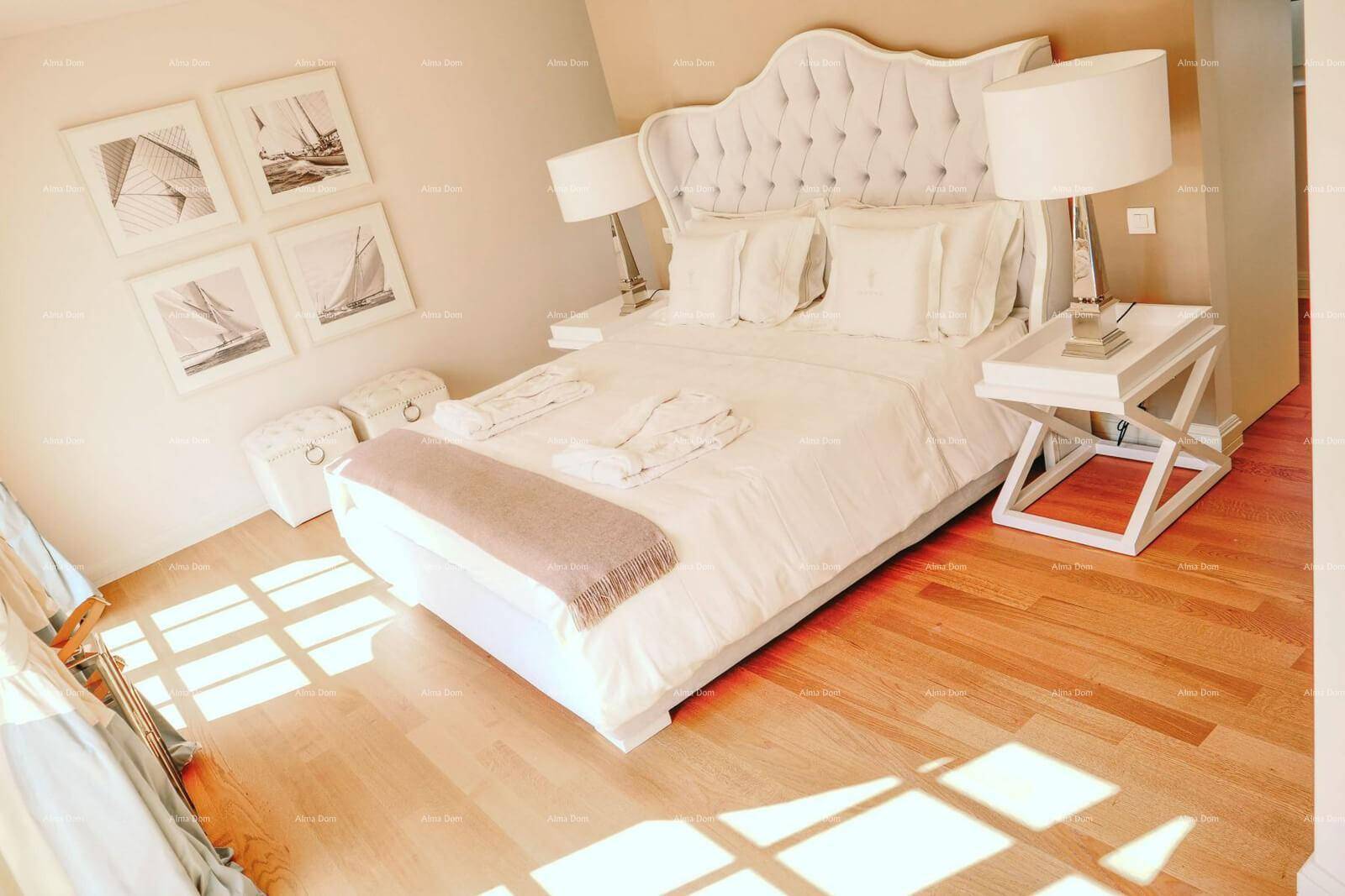 Elegantes Schlafzimmer mit großem, gepolstertem Bett, Holzboden und viel Tageslicht.