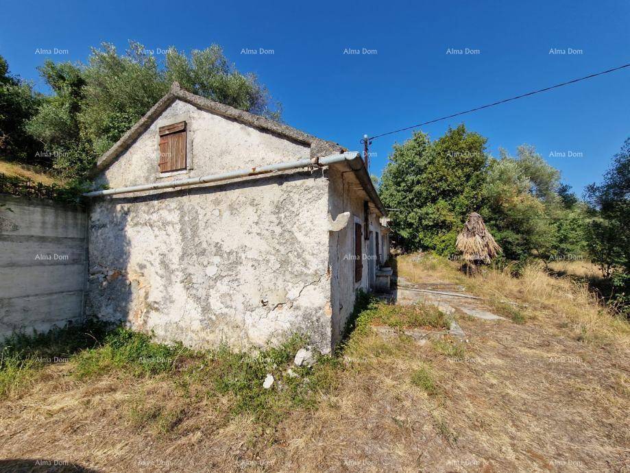 Altes, verfallenes Steinhaus mit bröckelndem Putz und Holztüren in ländlicher Umgebung.