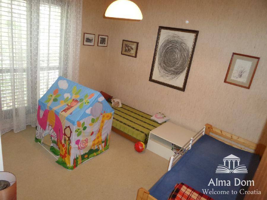 Kinderzimmer mit zwei Einzelbetten und einem bunten Spielzelt, hell und freundlich gestaltet.