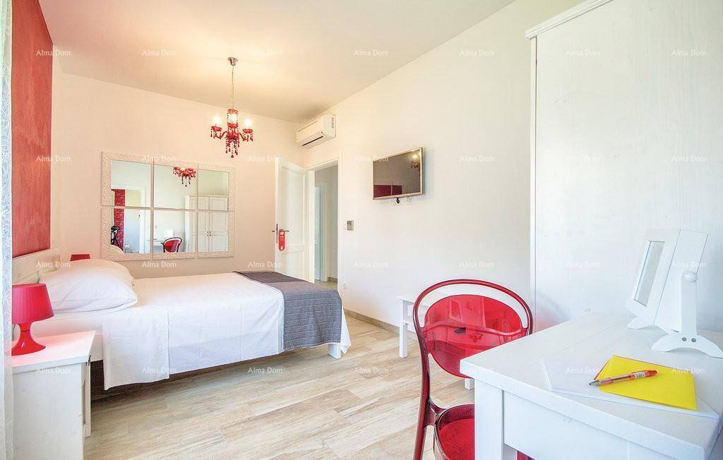 Schlafzimmer mit Schreibtisch, Wandfernseher und Blick auf den Außenbereich.