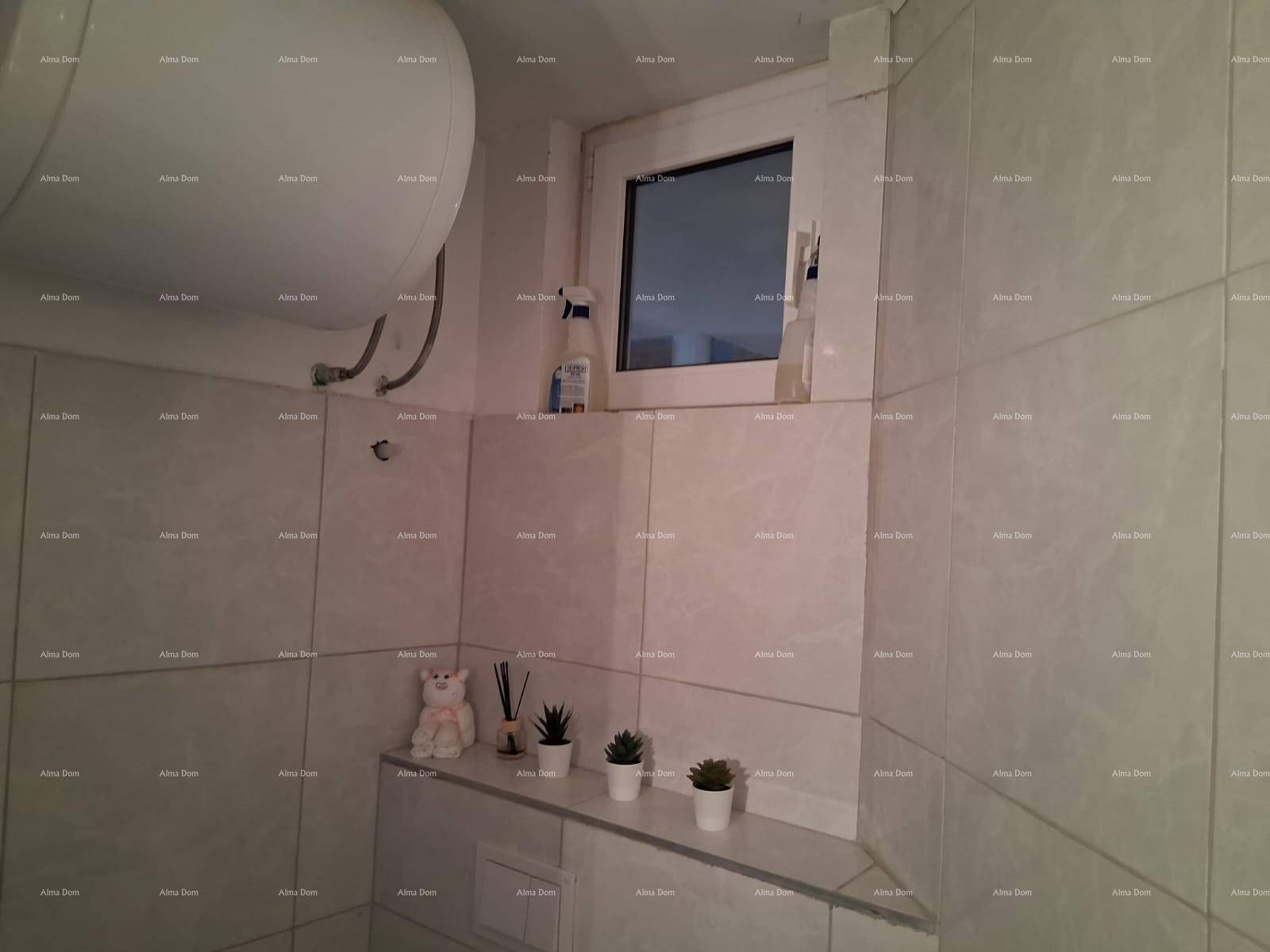 Badezimmer mit hellen Fliesen, Boiler und kleinem Fenster für natürliche Belüftung.