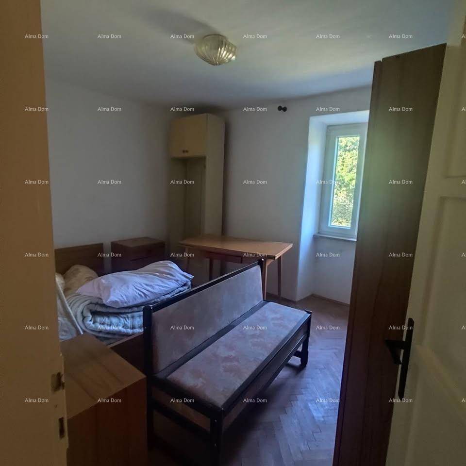 Einfaches Schlafzimmer mit Holzboden, kleinem Bett und einem Fenster mit Blick ins Grüne.