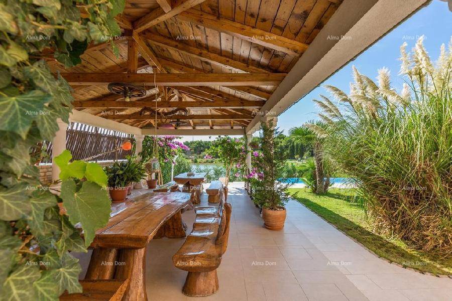 Überdachte Terrasse mit rustikalem Holztisch und Bänken, ideal für Mahlzeiten im Freien mit Gartenblick.