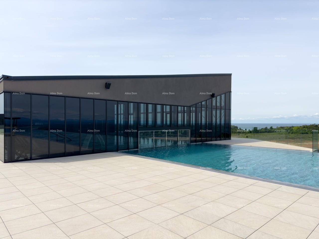 Modernes Gebäude mit großen dunklen Fenstern neben einem Außenpool, mit Blick auf das Meer.