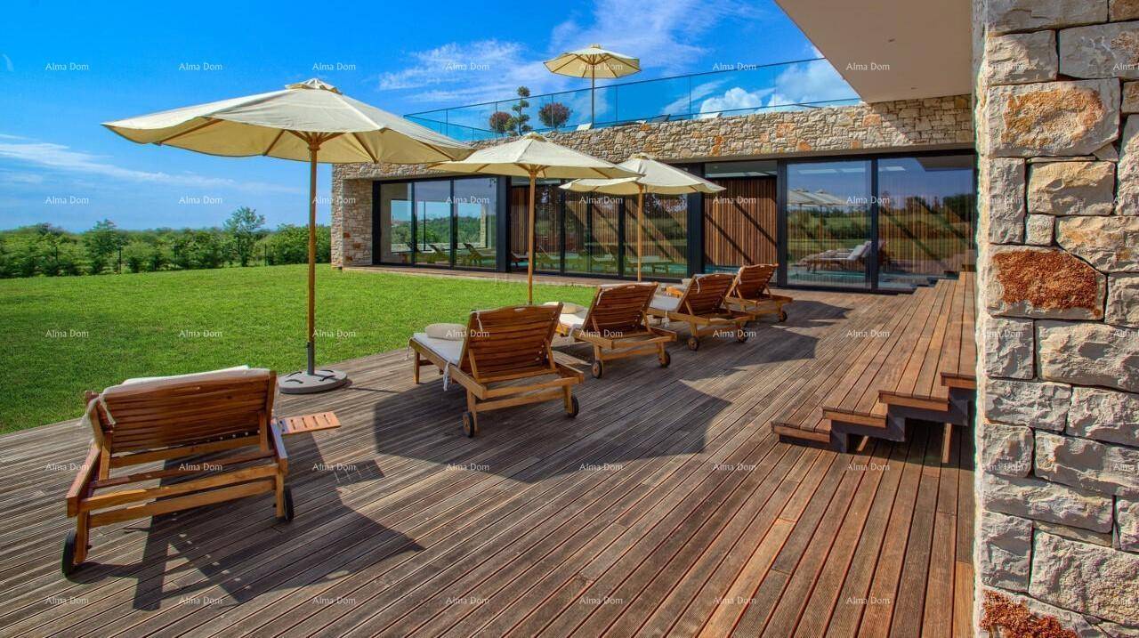 Weitläufige Holzterrasse mit bequemen Sonnenliegen und Sonnenschirmen, umgeben von Rasen und Natur.
