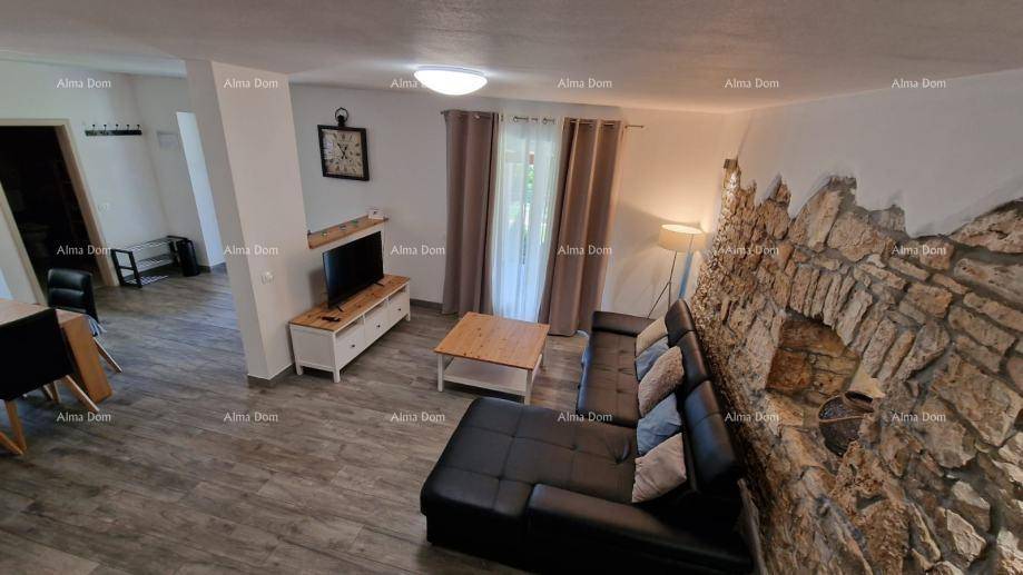 Gemütliches Wohnzimmer mit dunklem Sofa, Holzboden und einer dekorativen Steinwand, die Charakter verleiht.