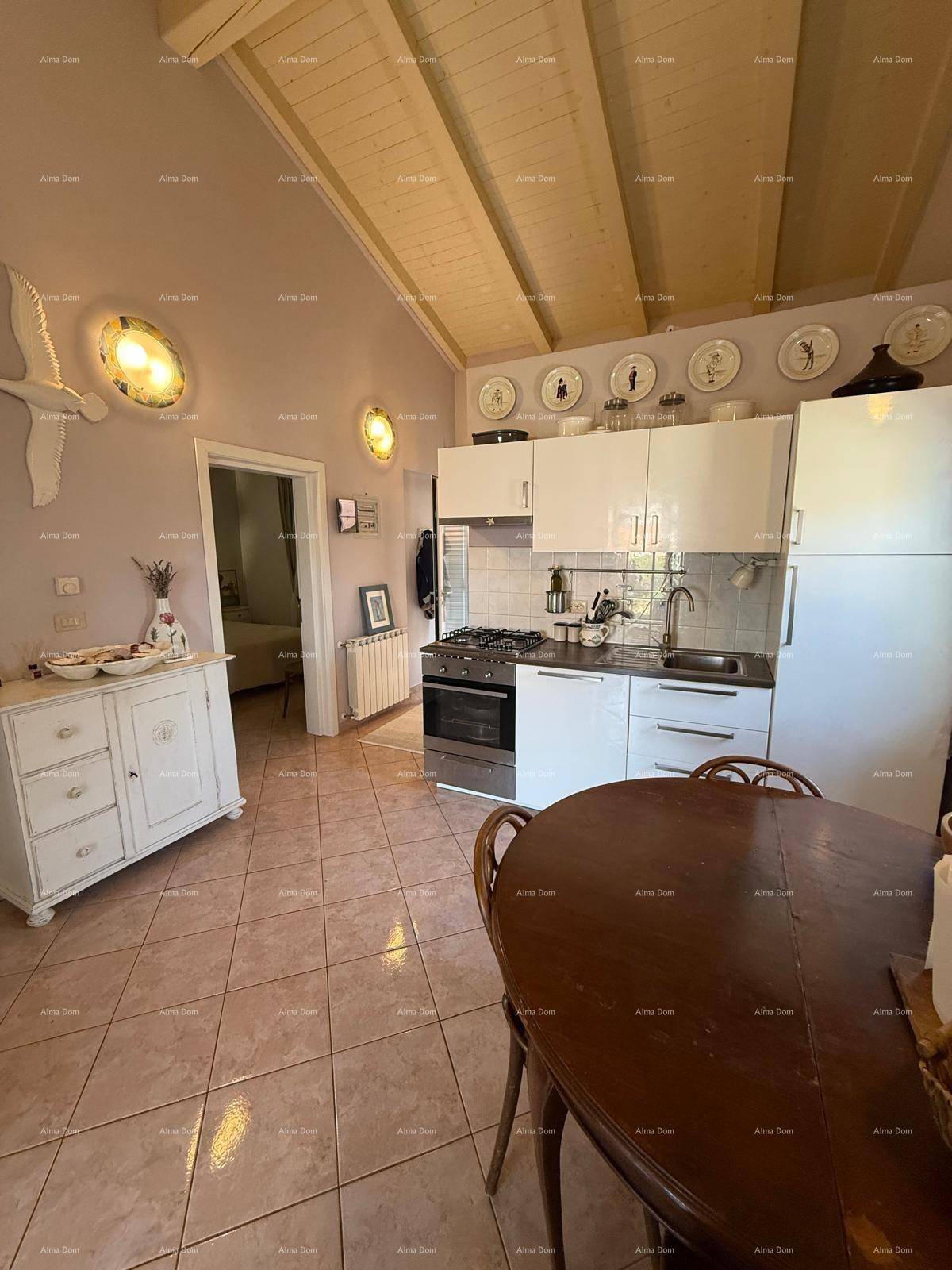 Helle Küche mit Essbereich, weißen Schränken und Holzbalkendecke, angrenzend an ein Schlafzimmer.