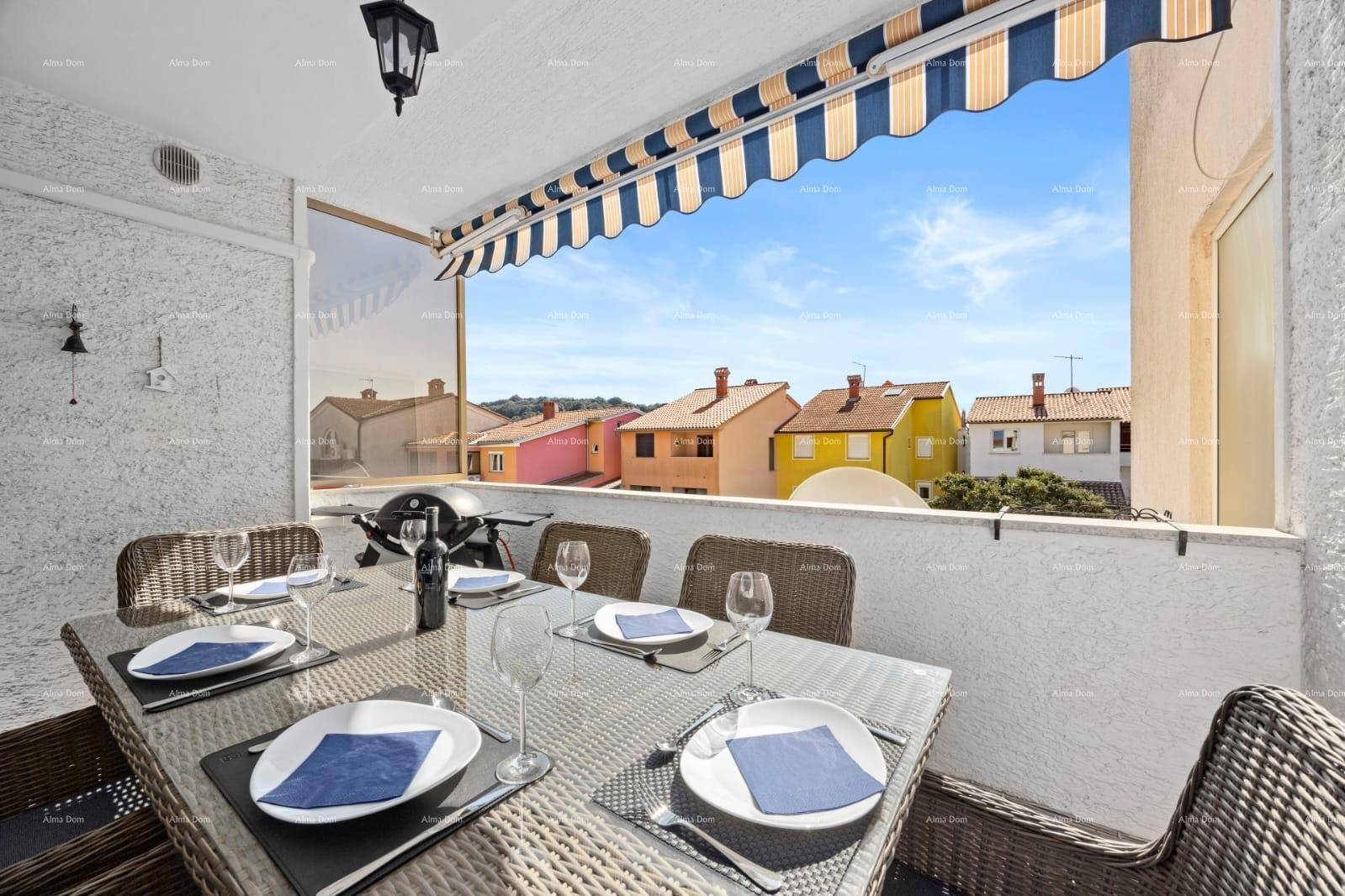 Sonniger Balkon mit Esstisch und Grill, bietet einen schönen Blick auf die umliegenden Häuser.