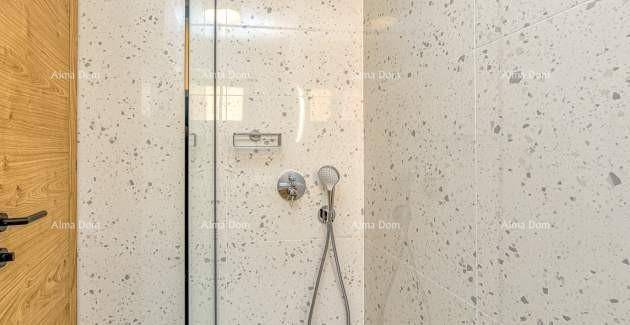 Duschbereich im modernen Badezimmer mit Glasabtrennung und gesprenkelten Wandfliesen.