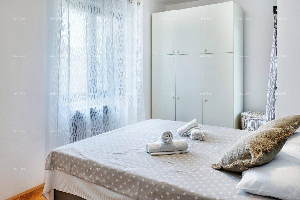 Schlafzimmer mit Doppelbett, weißen Einbauschränken und hellem Fenster mit Vorhängen.
