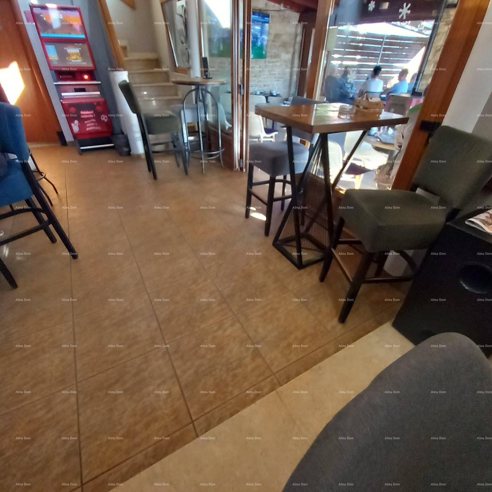 Innenansicht einer Bar mit Fliesenboden, Sitzgelegenheiten und Blick auf den Außenbereich.