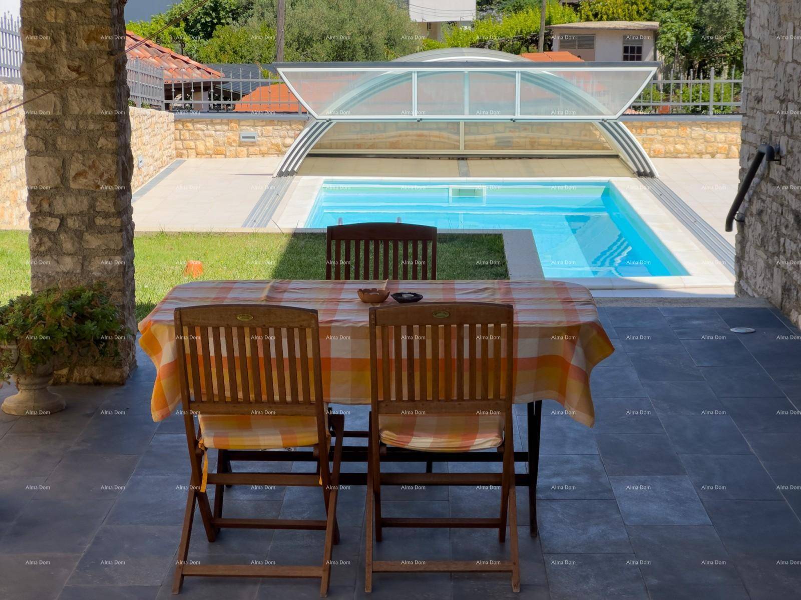 Terrasse mit Esstisch und Blick auf den Poolbereich mit verschiebbarer Abdeckung.