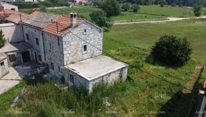 Altes Steinhaus mit Ziegeldach und umliegendem, verwildertem Grundstück in ländlicher Umgebung.