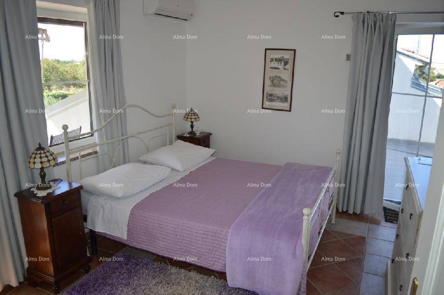 Helles Schlafzimmer mit Doppelbett, Kommode und Zugang zu einem Balkon, mit lila Bettwäsche.