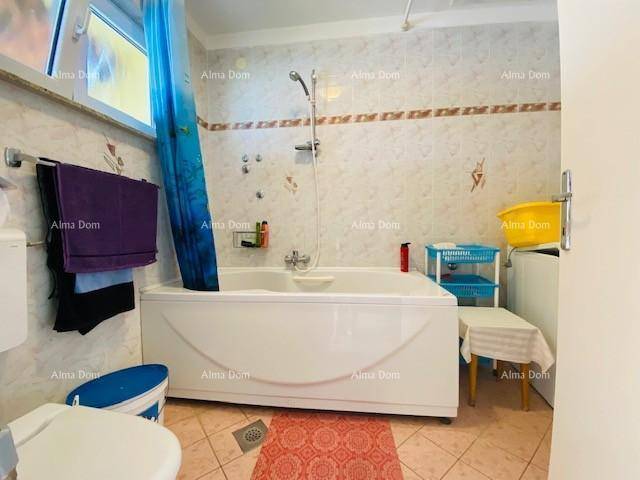 Badezimmer mit Badewanne und Duschvorhang, gefliesten Wänden und Fenster für Tageslicht.