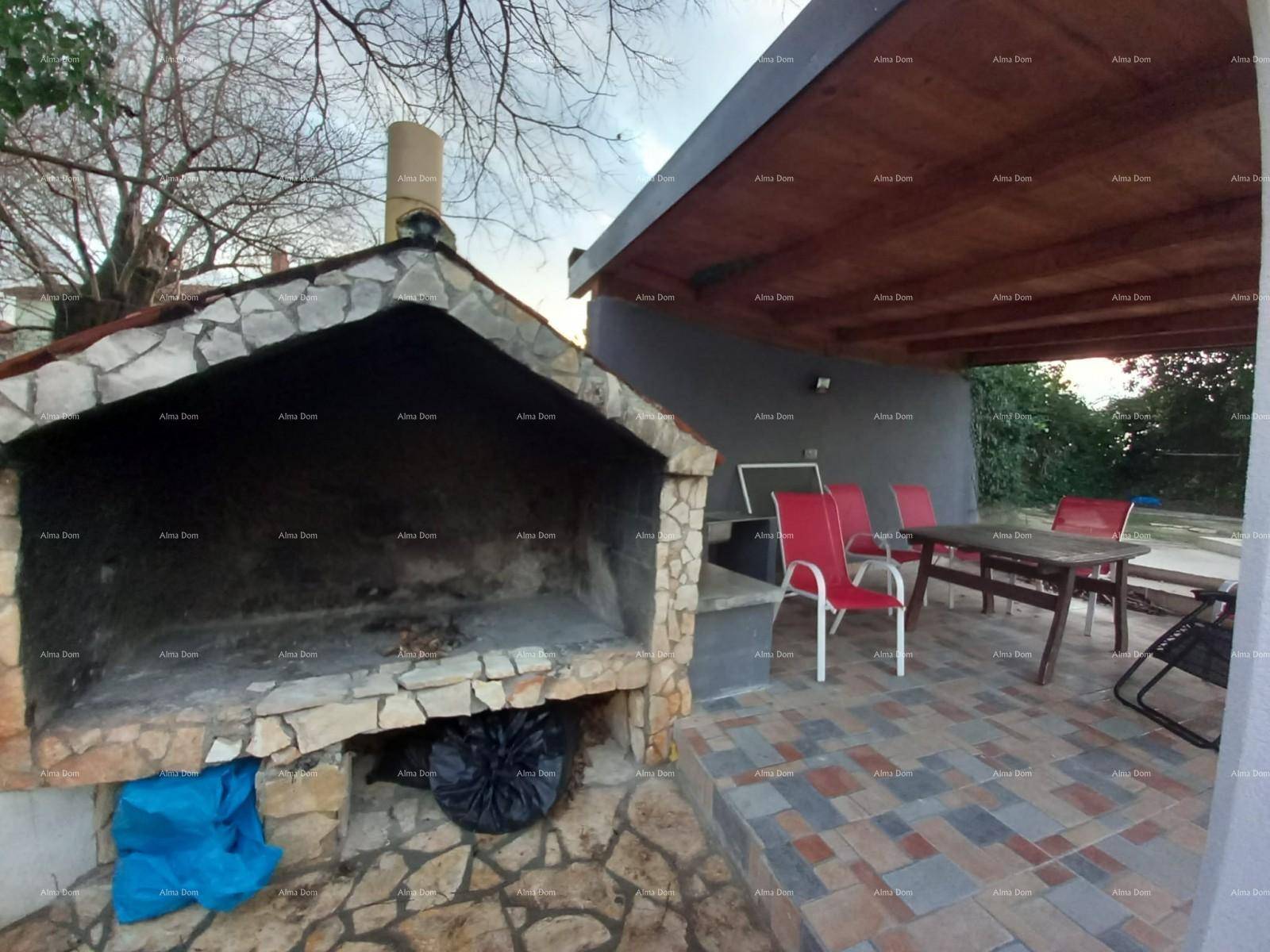 Detailansicht des gemauerten Grills und des überdachten Essbereichs im Freien mit Holztisch.