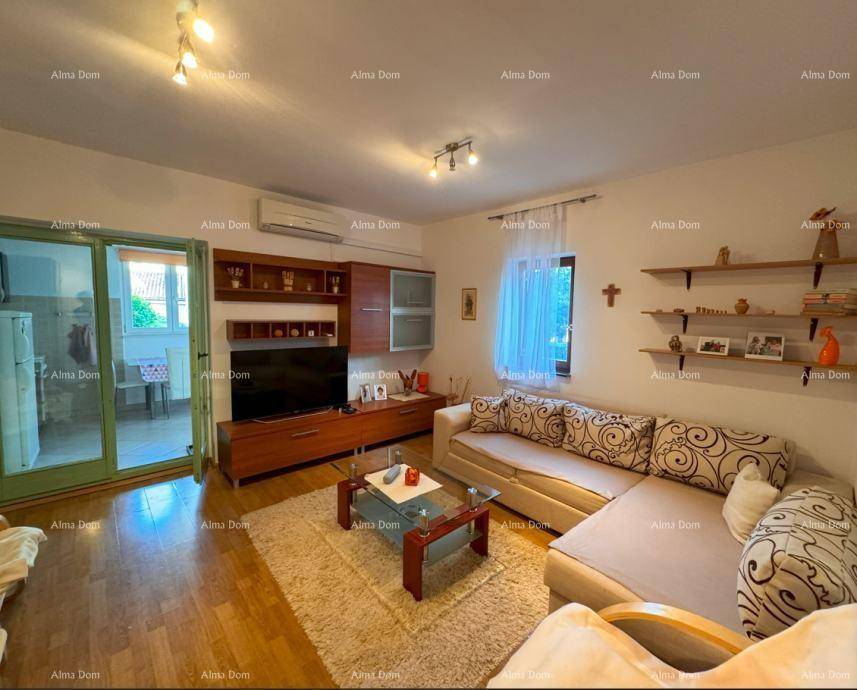 Gemütliches Wohnzimmer mit Sofa, TV-Möbel und Zugang zu einem weiteren Raum durch eine Glastür.