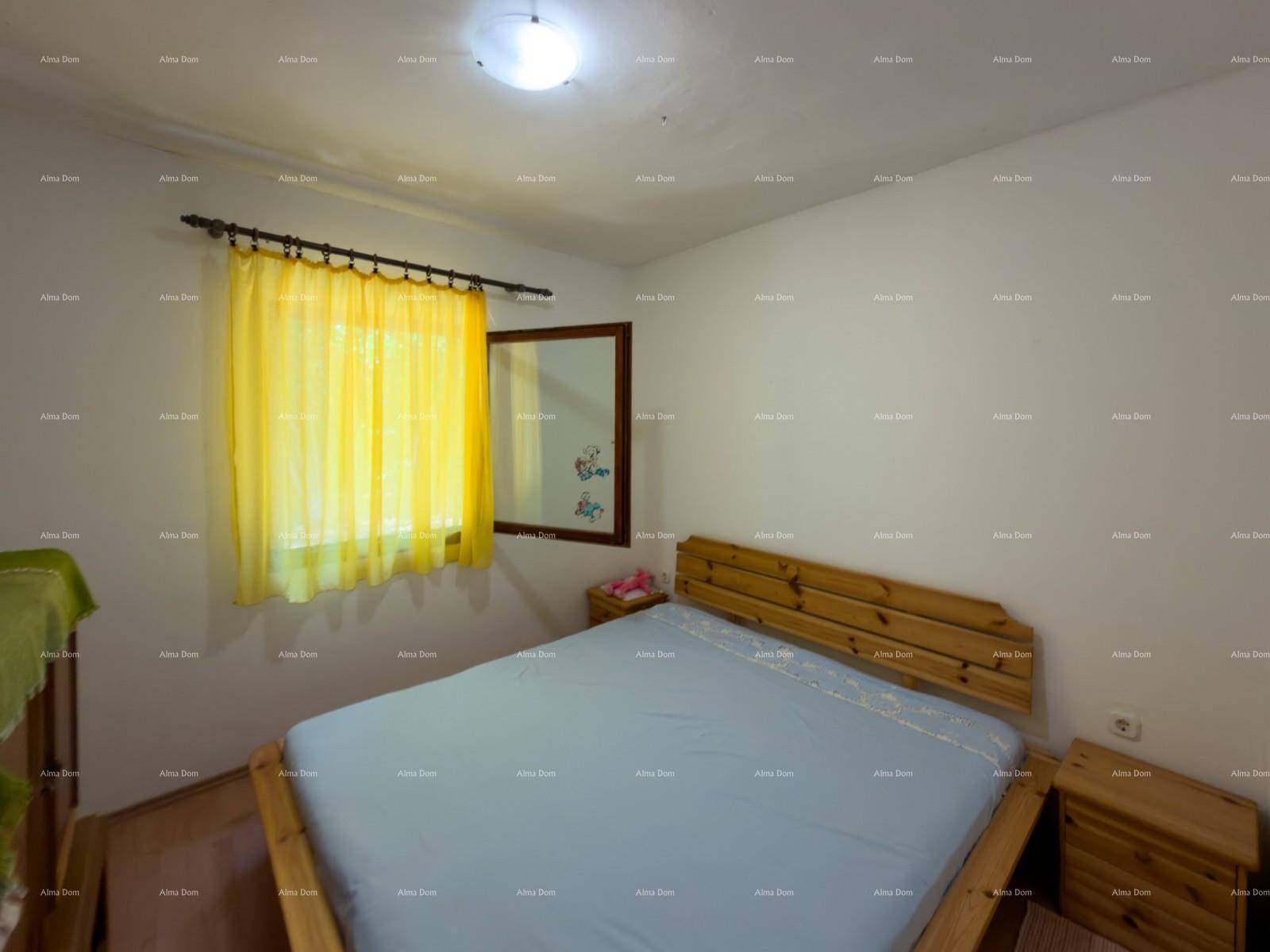 Schlafzimmer mit Holzdoppelbett und Nachttischen, gelbe Vorhänge sorgen für Farbakzente.