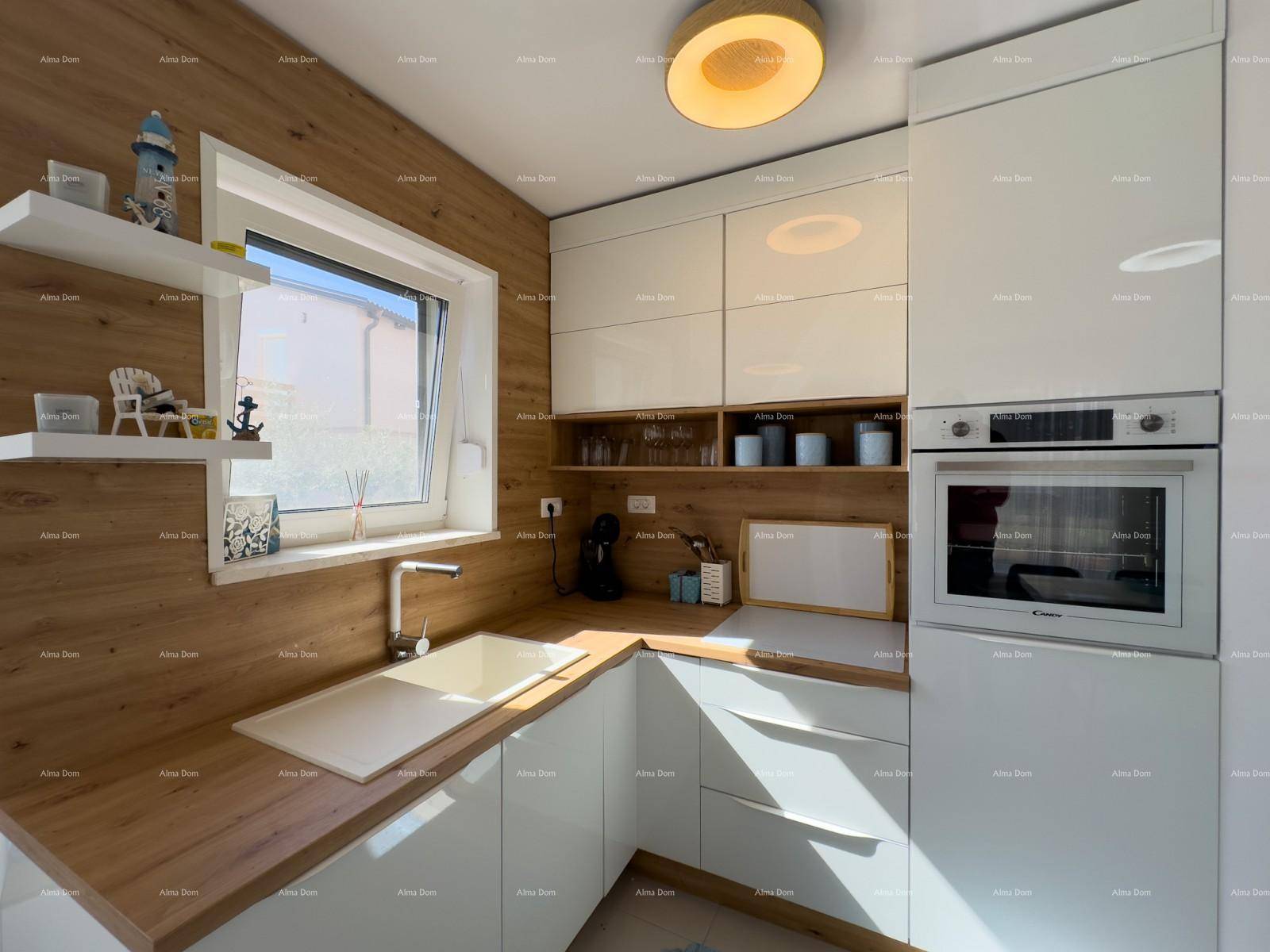 Moderne weiße Einbauküche mit Holzdetails, Backofen und Fenster.