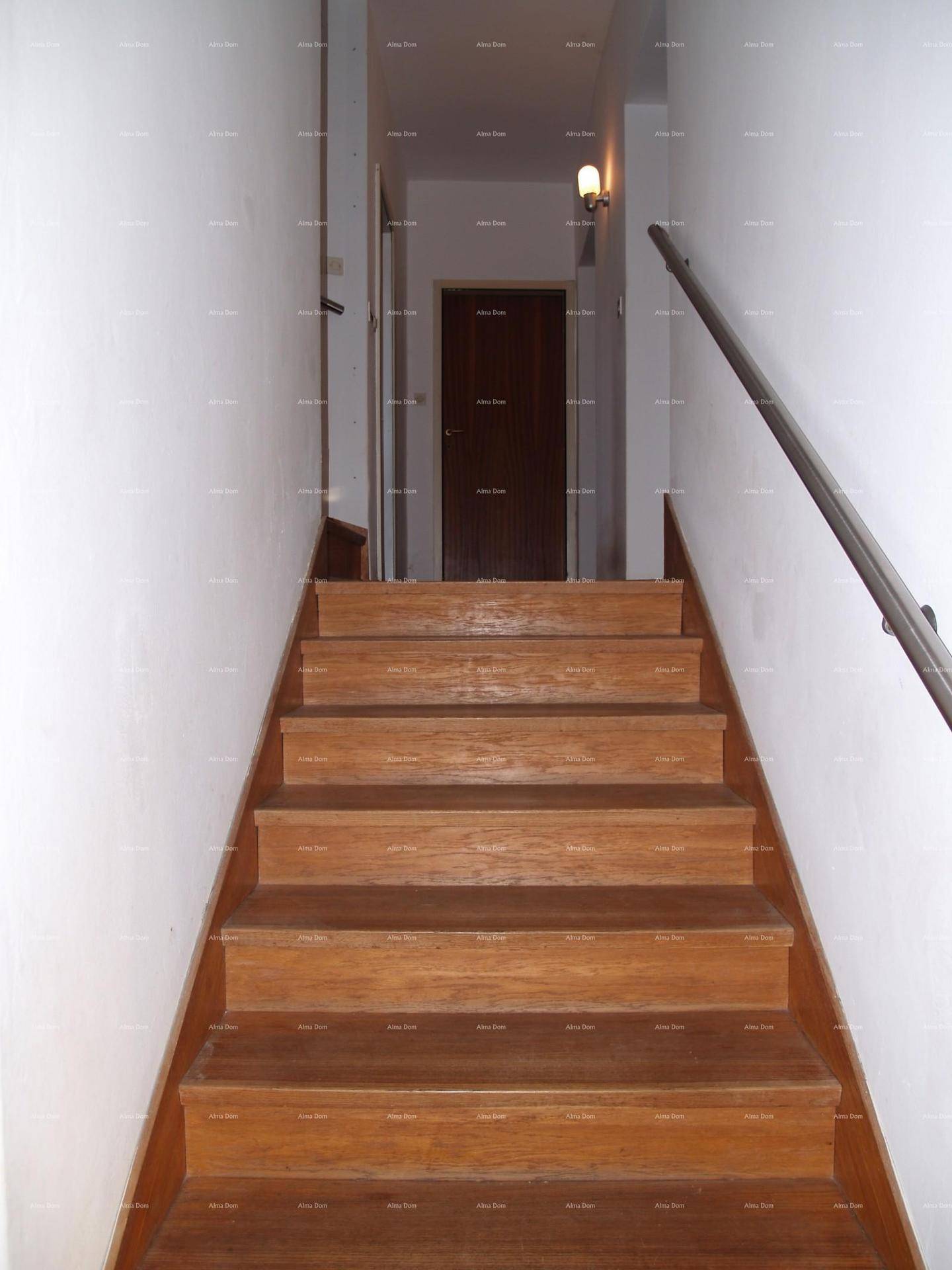 Holztreppe führt zu einem oberen Flur mit dunkler Tür und Handlauf.