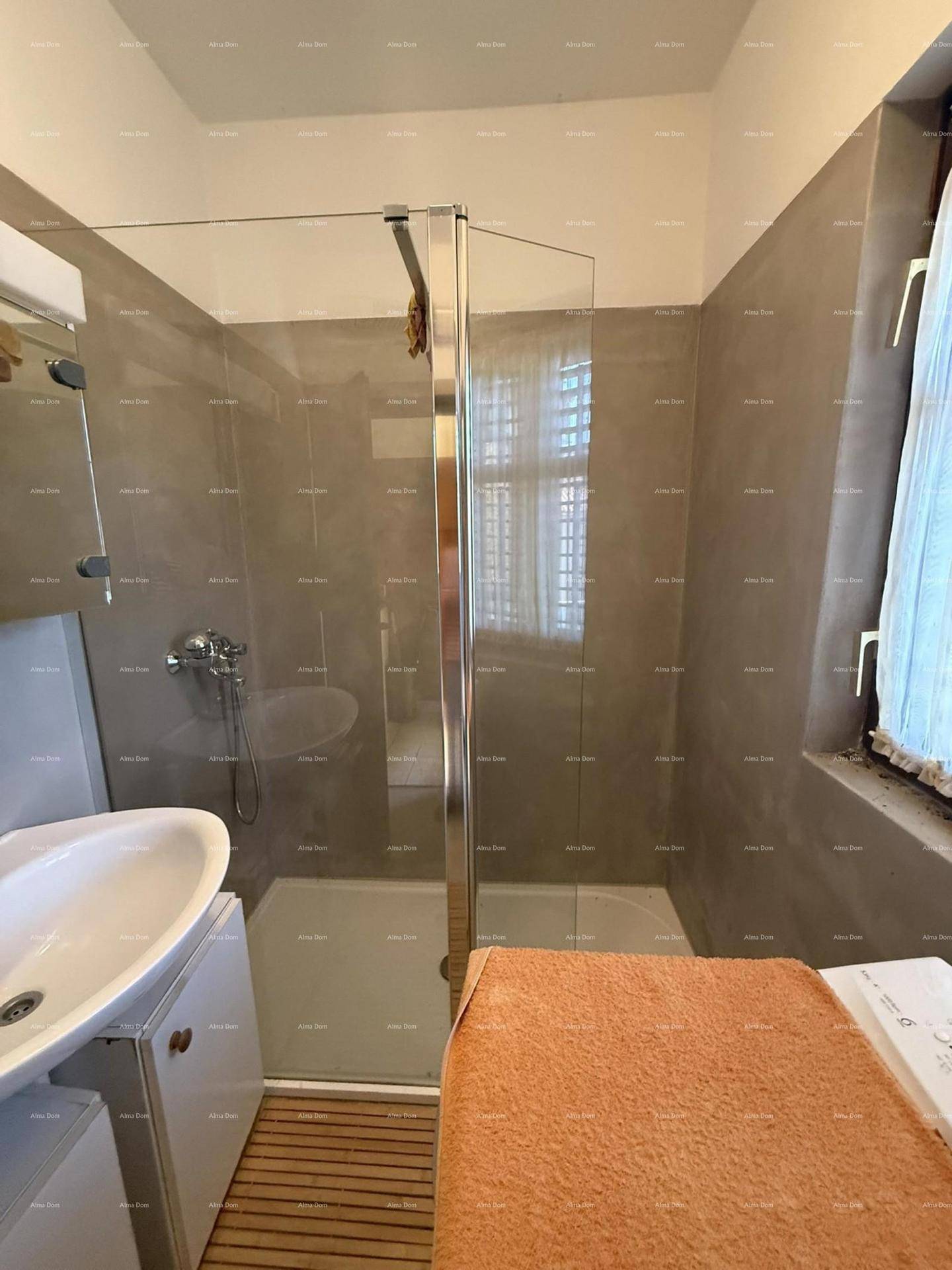 Modernisiertes Badezimmer mit Duschkabine, Waschbecken und Holzrost auf dem Boden.