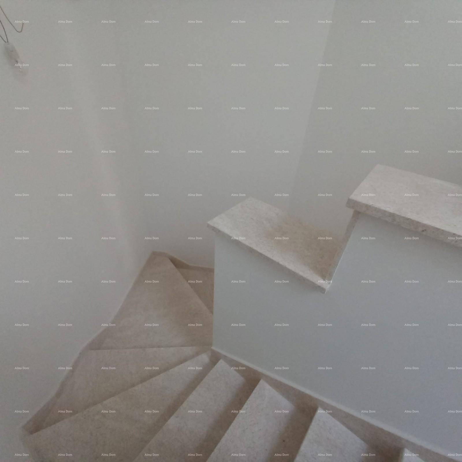 Treppenhaus mit hellen Stufen und weiß gestrichenen Wänden, die zu einem oberen Stockwerk führen.