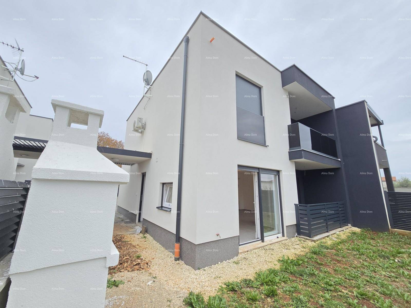 Neubau mit zeitgenössischer Architektur, weißer Fassade und dunklen Akzenten unter bewölktem Himmel.