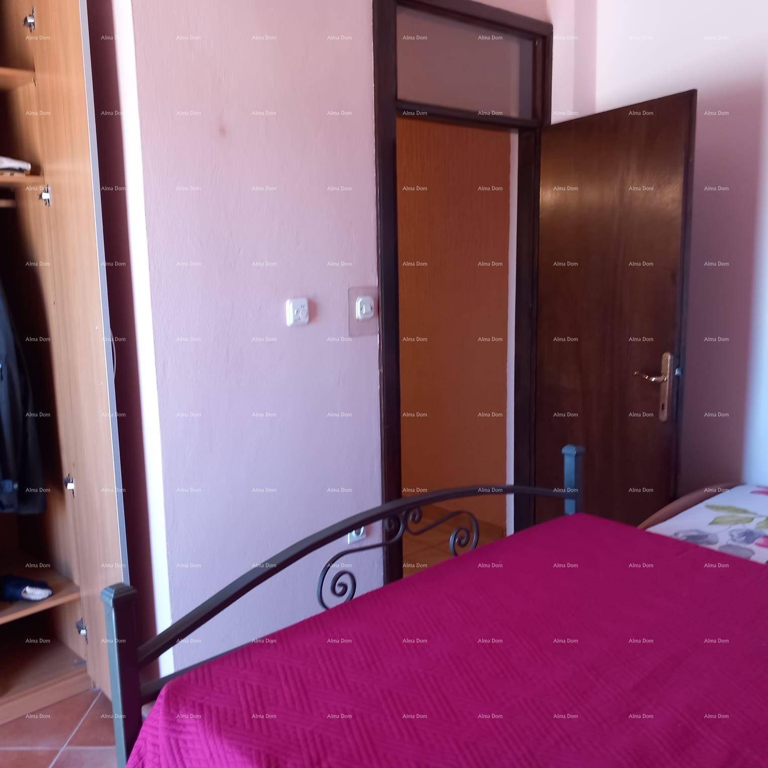 Schlafzimmer mit Metallbett, Kleiderschrank und Zugang zu einem weiteren Raum.
