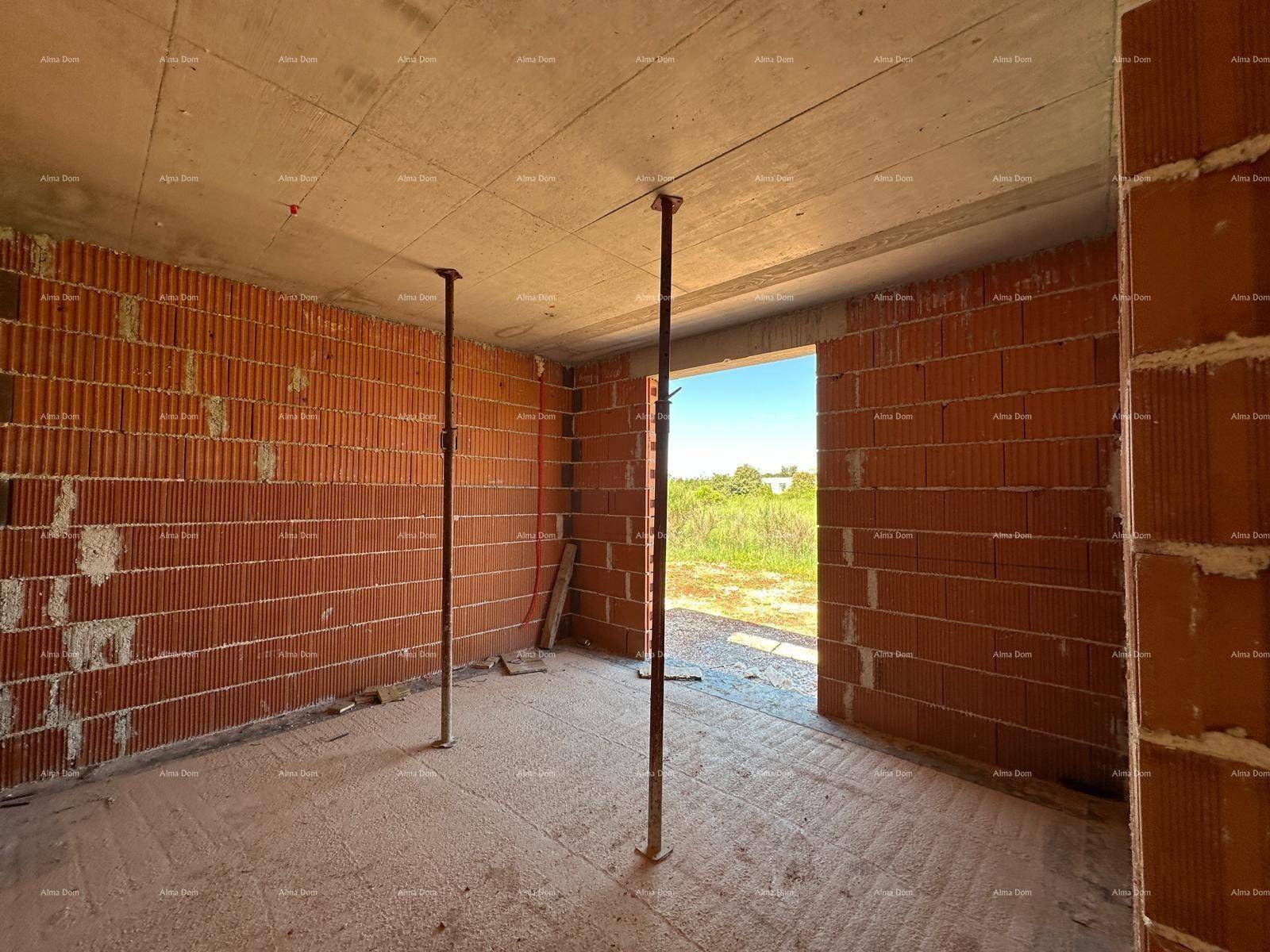 Unfertiger Innenraum mit Ziegelwänden, Betondecke und einer großen Öffnung zur Außenseite.
