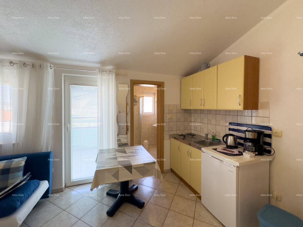 Funktionale Küchenzeile mit Kochfeld, Kühlschrank und direktem Zugang zum Balkon.