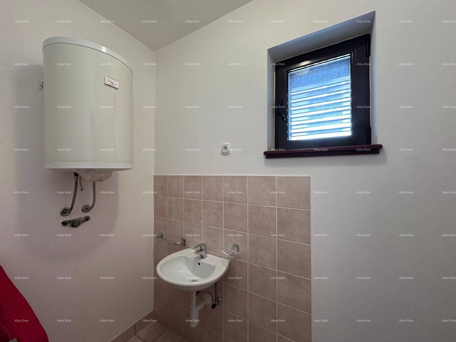 Kleiner WC-Raum mit Waschbecken, Warmwasserbereiter und Fenster, funktional und hell.