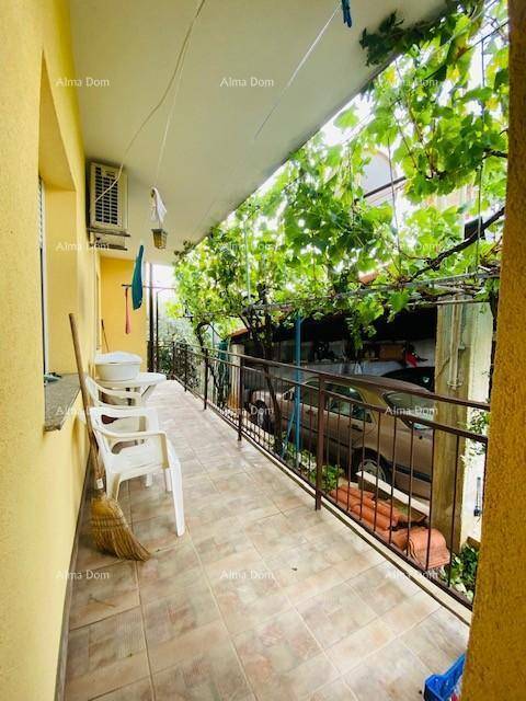 Überdachter Balkon mit Weinreben, Fliesenboden und einfacher Bestuhlung für entspannte Stunden.